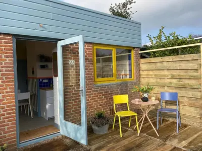 a tiny house with a patio with chairs and a table at Holiday Home in Noordwijkerhout near Lake in Noordwijkerhout