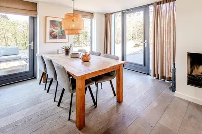 a dining room with a wooden table and chairs at Villa Koperwiek in Egmond aan den Hoef
