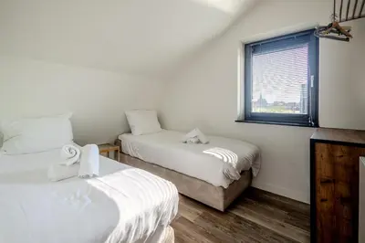a bedroom with two beds and a window at Villa Koperwiek in Egmond aan den Hoef