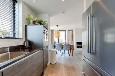 a kitchen with a stainless steel refrigerator and a dining room at Villa Koperwiek in Egmond aan den Hoef