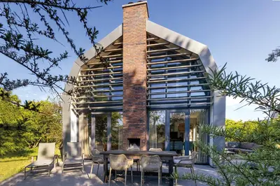 a glass house with a brick chimney and a table and chairs at Villa Koperwiek in Egmond aan den Hoef