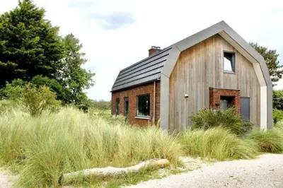 a small wooden house in a field of tall grass at Villa Goudvink in Egmond aan den Hoef