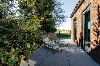 two chairs on a patio next to a brick building at Villa Goudvink in Egmond aan den Hoef