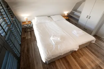 a bedroom with a bed with white sheets and two towels at Villa Goudvink in Egmond aan den Hoef