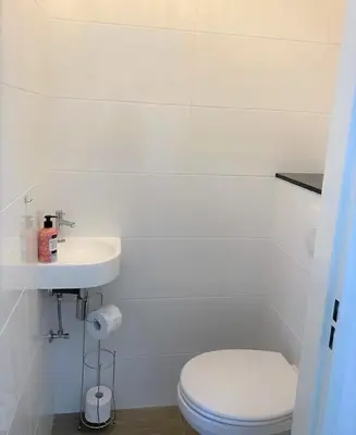 a white bathroom with a toilet and a sink at Sterflat 33 - 
