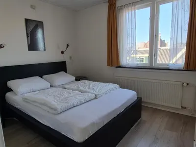 a bed in a bedroom with a large window at De Groten Zes in Egmond aan Zee