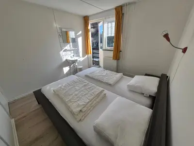 a small bedroom with two beds and a window at De Groten Zes in Egmond aan Zee