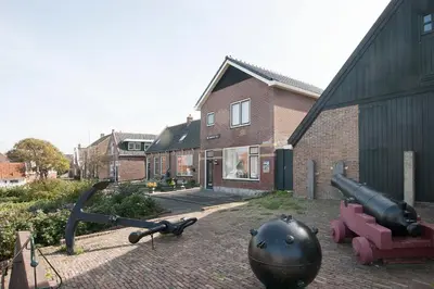 a house with a cannon and a cannon ball on the ground at De Groten Zes in Egmond aan Zee