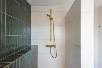 a shower in a bathroom with white tiles at Coastal Inn in Zandvoort