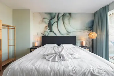 a bedroom with a large white bed with a painting at Coastal Inn in Zandvoort