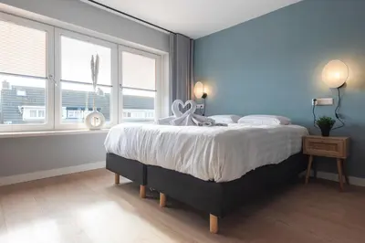 a bedroom with a large bed with blue walls and windows at Coastal Inn in Zandvoort