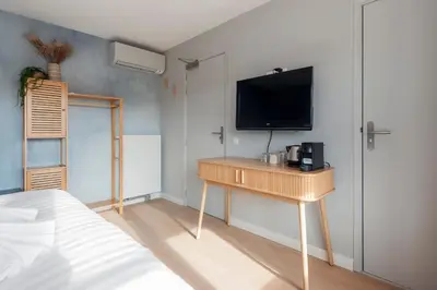 a bedroom with a desk with a tv on the wall at Coastal Inn in Zandvoort