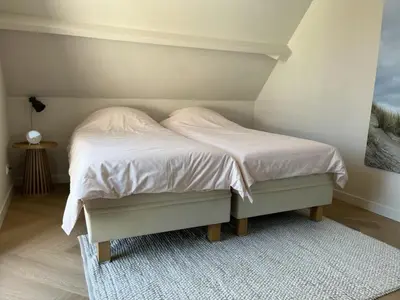 a bedroom with a bed with white sheets and a rug at Salty Breeze in Noordwijk