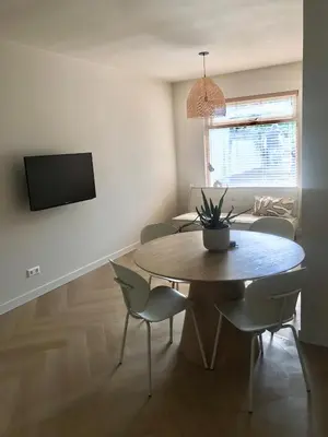 a dining room with a table and chairs and a television at Salty Breeze in Noordwijk