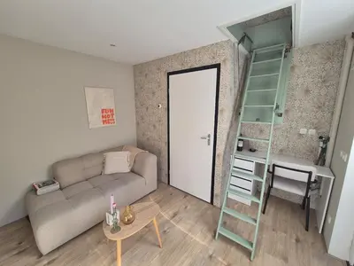 a living room with a couch and a table and a ladder at Vlier aan zee in Katwijk aan Zee