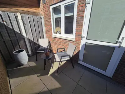 a patio with two chairs and a large screen television at Vlier aan zee in Katwijk aan Zee