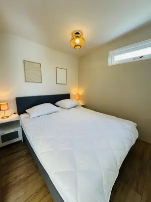 a large white bed in a bedroom with a window at Willem's Beachhouse in Noordwijk