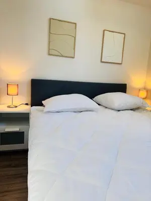 a bedroom with a white bed with two lamps at Willem's Beachhouse in Noordwijk