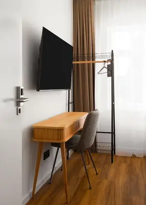 a wooden desk with a chair and a television on a wall at Limehome Utrecht Balijelaan in Utrecht
