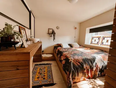 a bedroom with a bed and a dresser and a window at de Bunker Katwijk in Katwijk