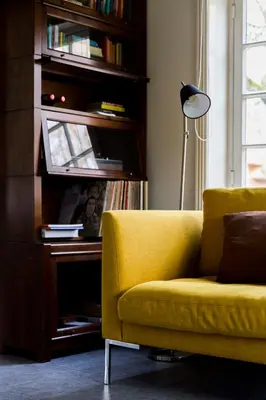a living room with a yellow couch and a lamp at Louisehoeve Holiday Home in Linschoten