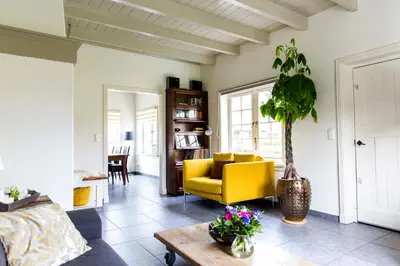 a living room with a yellow chair and a table at Louisehoeve Holiday Home in Linschoten