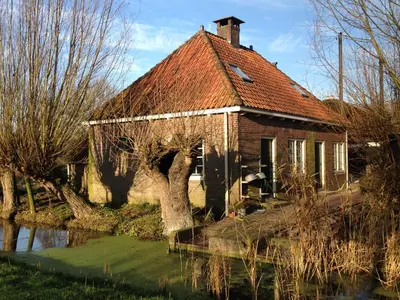 an old brick house next to a body of water at Louisehoeve Holiday Home in Linschoten