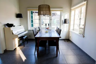 a dining room with a table and a piano at Louisehoeve Holiday Home in Linschoten