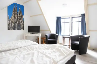 a bedroom with a bed and two chairs and a tv at La Casita bed and breakfast in Voorschoten