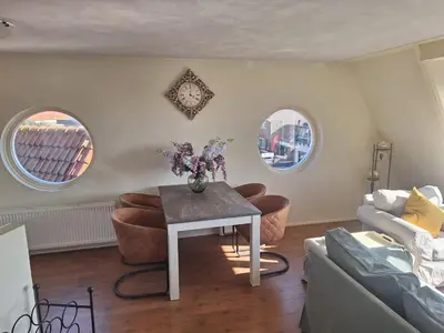 a living room with a table and three circular windows at Have a nice stay! - Juul's Rooftop, free parking in Noordwijk