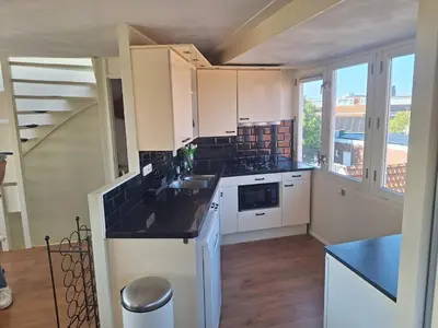 a kitchen with white cabinets and a black counter top at Have a nice stay! - Juul's Rooftop, free parking in Noordwijk