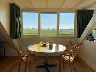a table and chairs in a room with two windows at Amsterdam Garden Studio in Uitdam