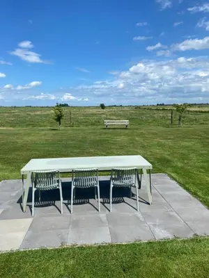 a picnic table with three chairs and a bench in a field at Amsterdam Garden Studio in Uitdam