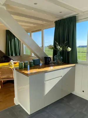 a kitchen with a staircase and green curtains at Amsterdam Garden Studio in Uitdam