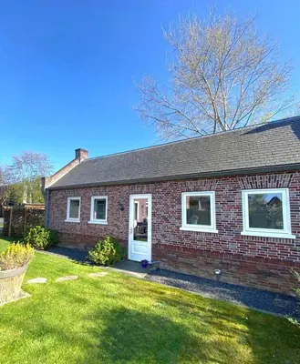 a red brick house with a white door at Huisje Suus, inclusief jacuzzi, kano en kajak in Zuid-Scharwoude