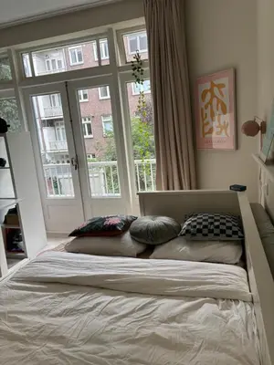 a bedroom with a bed with pillows and a window at 185m2 groot appartement met tuin in City Centre in Amsterdam