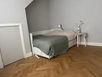 a small bedroom with a bed and a wooden floor at 185m2 groot appartement met tuin in City Centre in Amsterdam