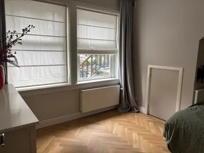 a bedroom with two windows and a wooden floor at 185m2 groot appartement met tuin in City Centre in Amsterdam