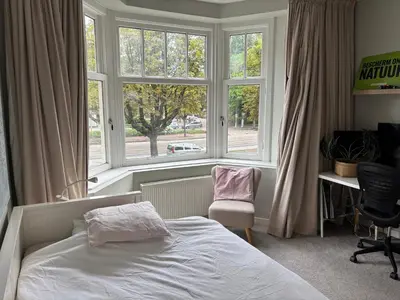 a bedroom with a bed and a window and a chair at 185m2 groot appartement met tuin in City Centre in Amsterdam
