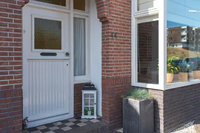 a brick house with a white door and a window at Le Paysan in Wijk aan Zee