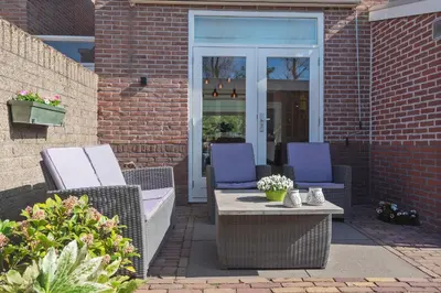 two wicker chairs and a table on a patio at Le Paysan in Wijk aan Zee