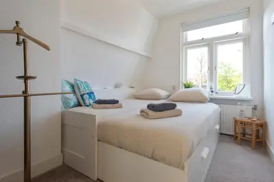two beds in a white room with a window at Le Paysan in Wijk aan Zee