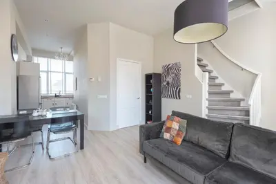 a living room with a black couch and a staircase at De Sonnehoeck Zandvoort in Zandvoort
