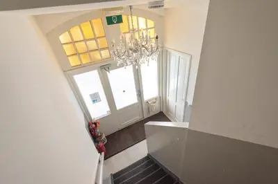 a staircase with a chandelier in a room with windows at De Sonnehoeck Zandvoort in Zandvoort