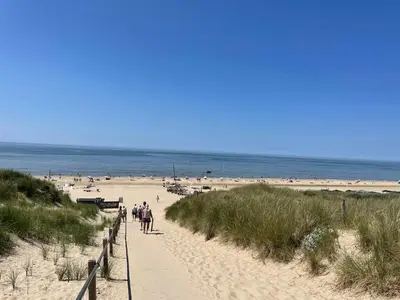 a group of people walking down a sandy beach at Tiny House Egmond in Egmond aan den Hoef