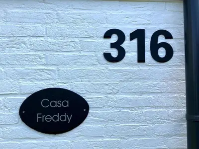 a sign on the side of a white brick wall at Casa Freddy in Noordwijkerhout