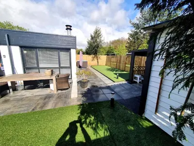 a small backyard with a wooden table and a fence at Casa Freddy in Noordwijkerhout