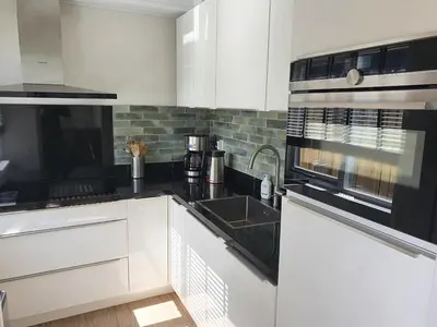 a kitchen with white cabinets and black counter tops at Casa Freddy in Noordwijkerhout