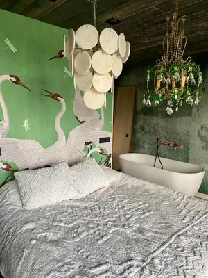 a bedroom with a bed and a bath tub and a chandelier at Hidden Gem in Oost-Knollendam