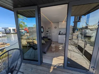 a house with glass doors and a view of the water at Gezellige houseboat Eclipse Monnickendam nabij Amsterdam in Monnickendam